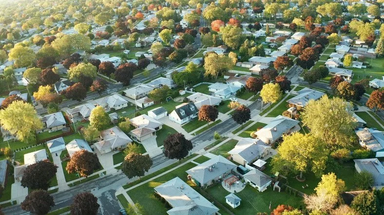 Aerial view of a suburban neighborhood with numerous trees, houses, and well-maintained streets.