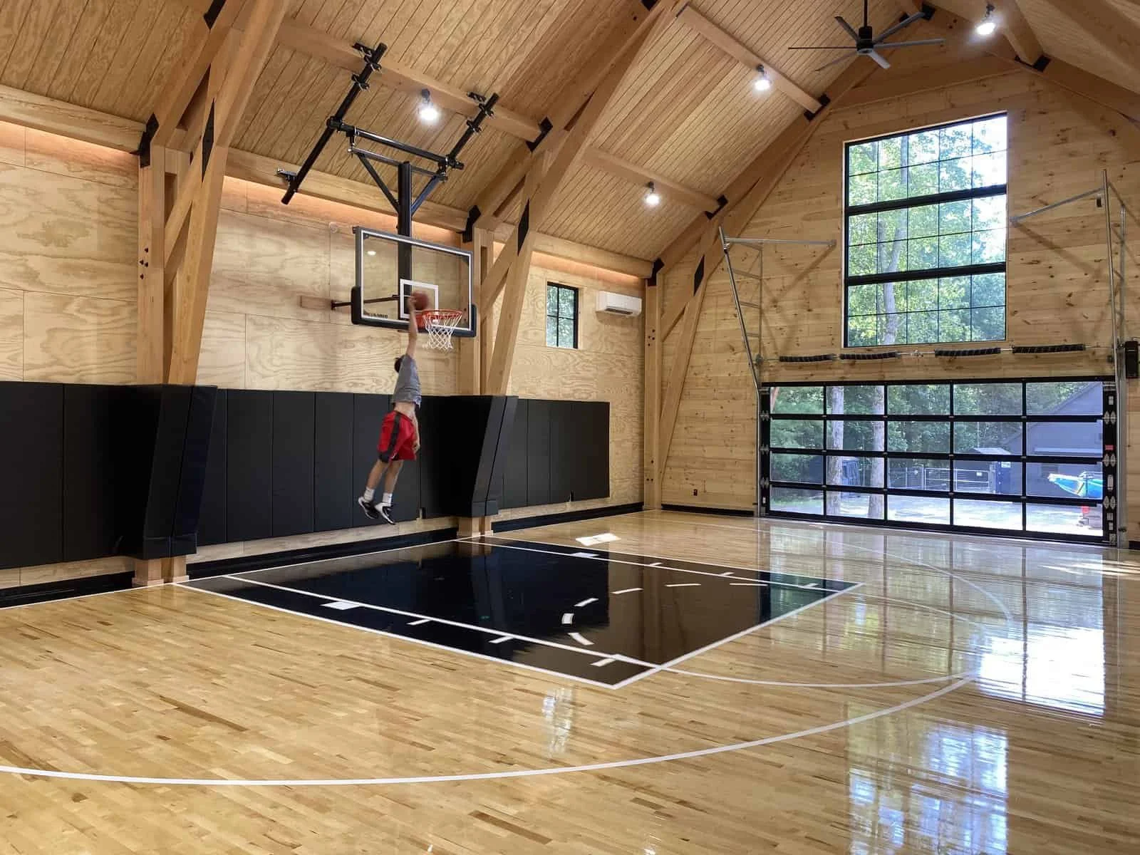A young boy in a gymnasium jumping to make a slam dunk shot in a basketball hoop.