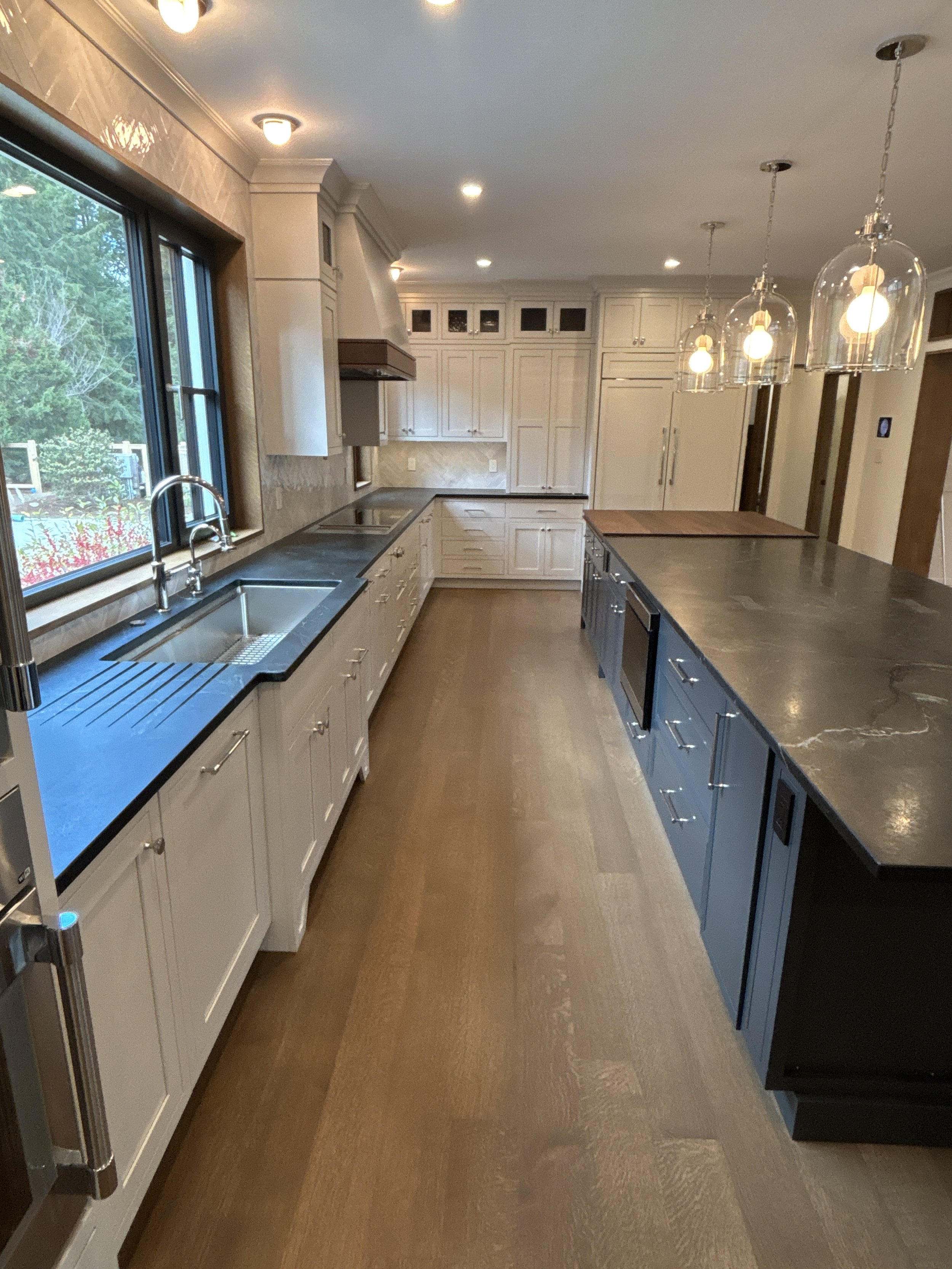 Best general contractor, home builder, and home remodeler on the Northshore in Andover, Massachusetts (MA), developed this modern high spacious kitchen with white cabinets, a large central island, pendant lighting, and an energy efficient window.