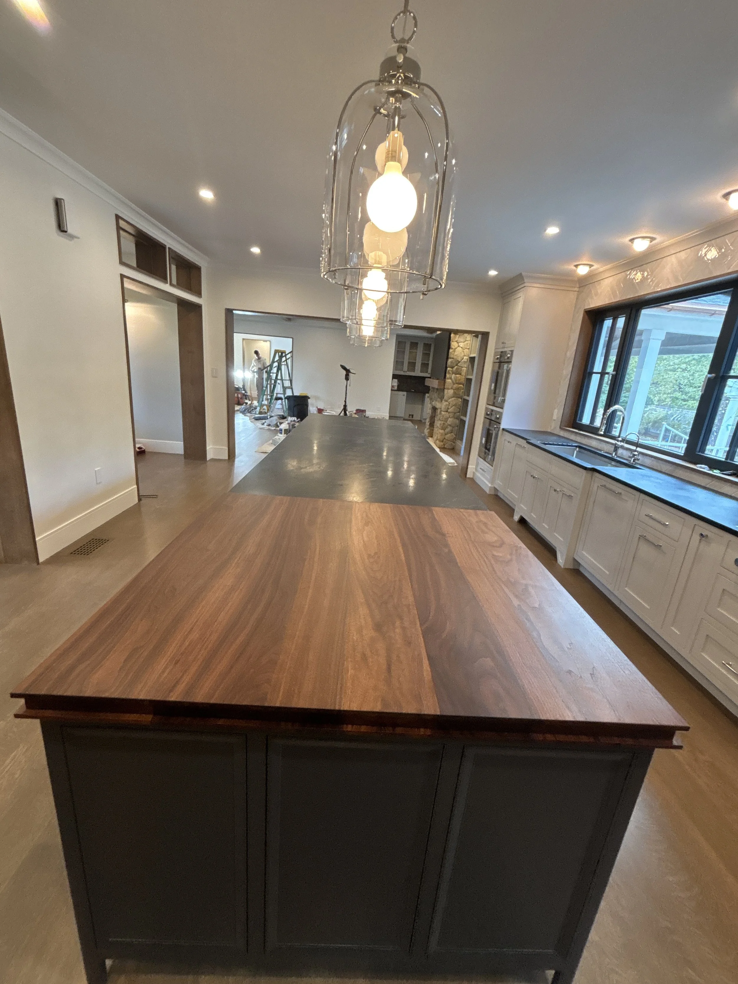 Best general contractor, home builder, and home remodeler on the Northshore in Andover, Massachusetts (MA), developed this modern high spacious kitchen with white cabinets, a large central island, pendant lighting, and an energy efficient window.