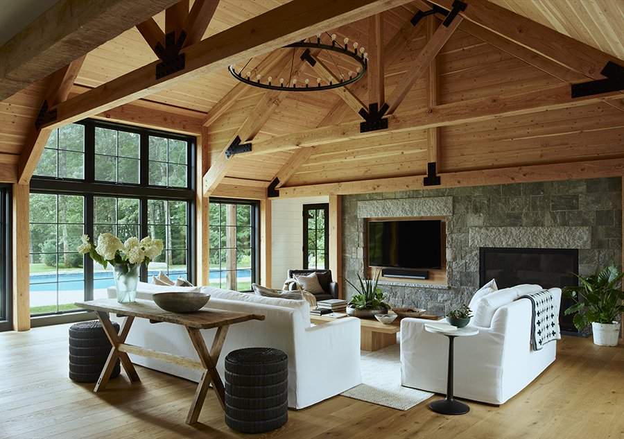 Living room with large windows, wooden ceiling, and stone fireplace.