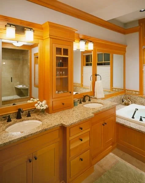 Bathroom with double vanity sinks, granite countertops, wooden cabinets, and a large mirror. There is a whirlpool bathtub and a walk-in shower visible in the background.