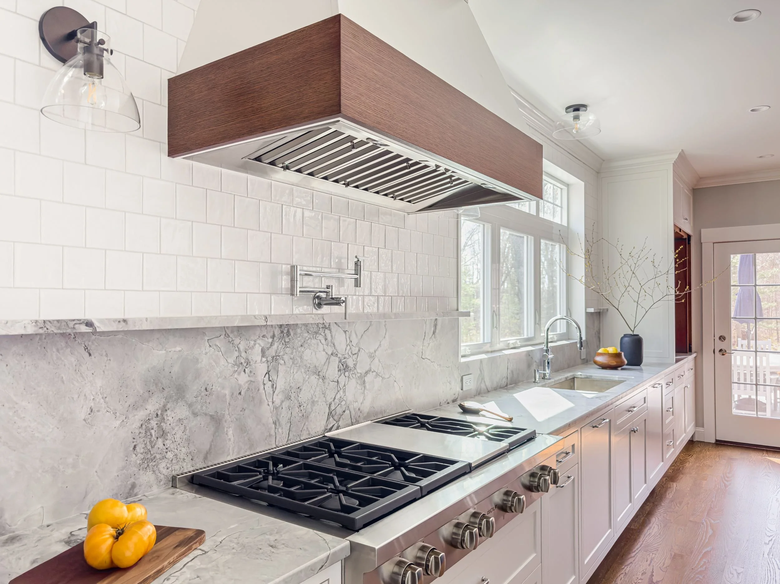 Best general contractor, home builder, and home remodeler on the Northshore in Andover, Massachusetts (MA), developed this modern high spacious kitchen with white cabinets, a large central island, pendant lighting, and an energy efficient window.