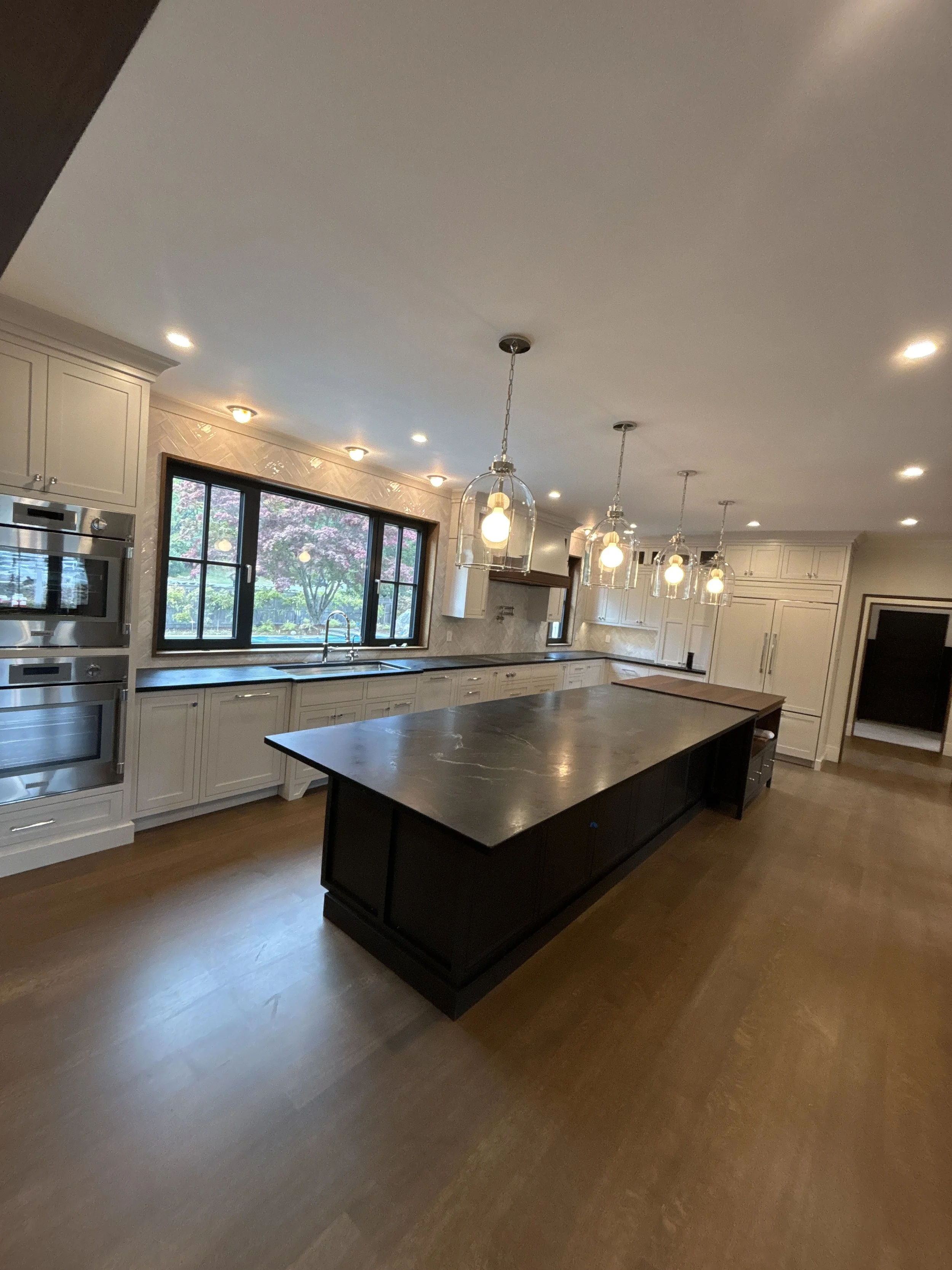 Best general contractor, home builder, and home remodeler on the Northshore in Andover, Massachusetts (MA), developed this modern high spacious kitchen with white cabinets, a large central island, pendant lighting, and an energy efficient window.
