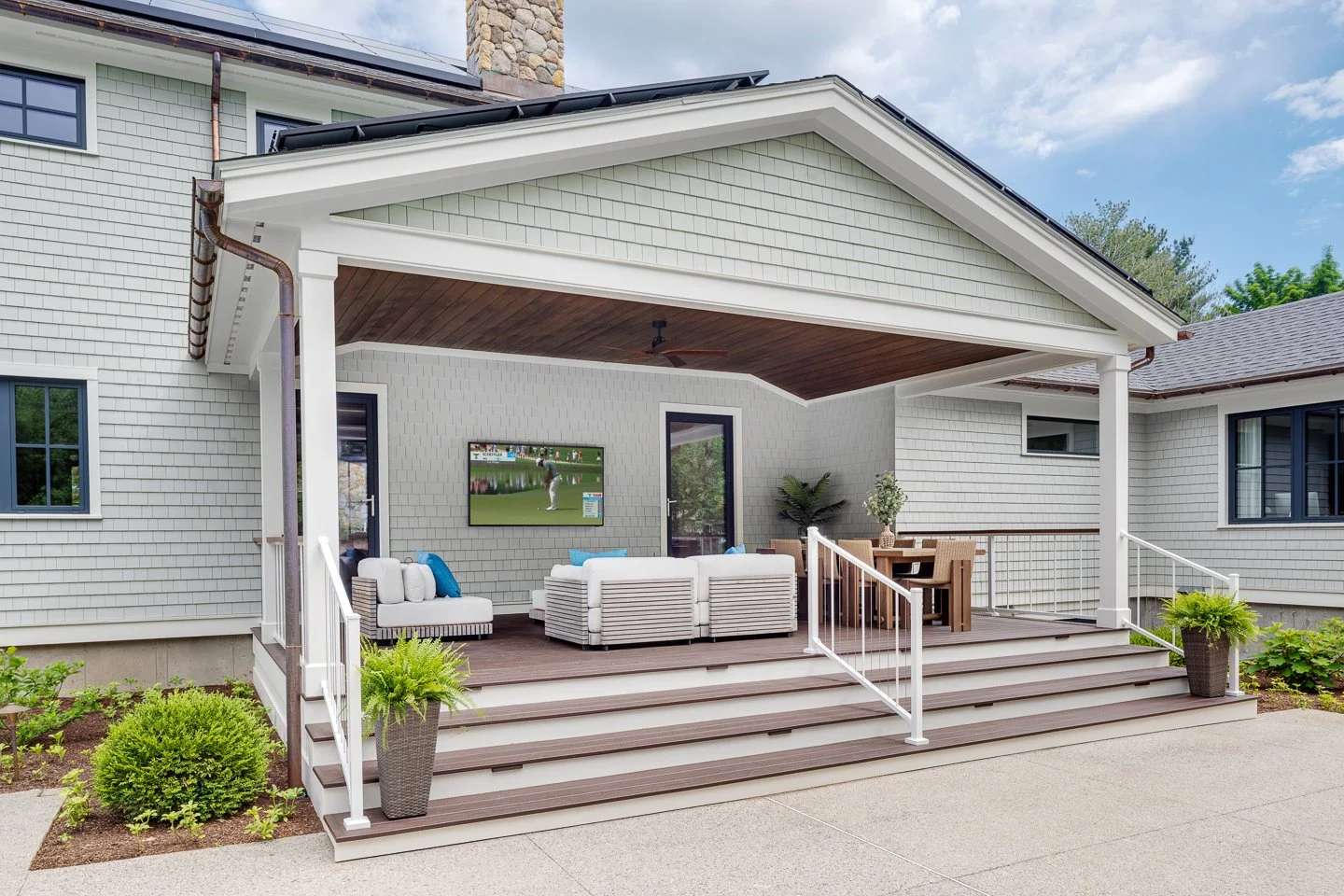 Best general contractor, home builder, and home remodeler on the Northshore in Andover, Massachusetts (MA), developed this modern outdoor living room and dining room, with an  outdoor TV, and stairs leading down to the yard.