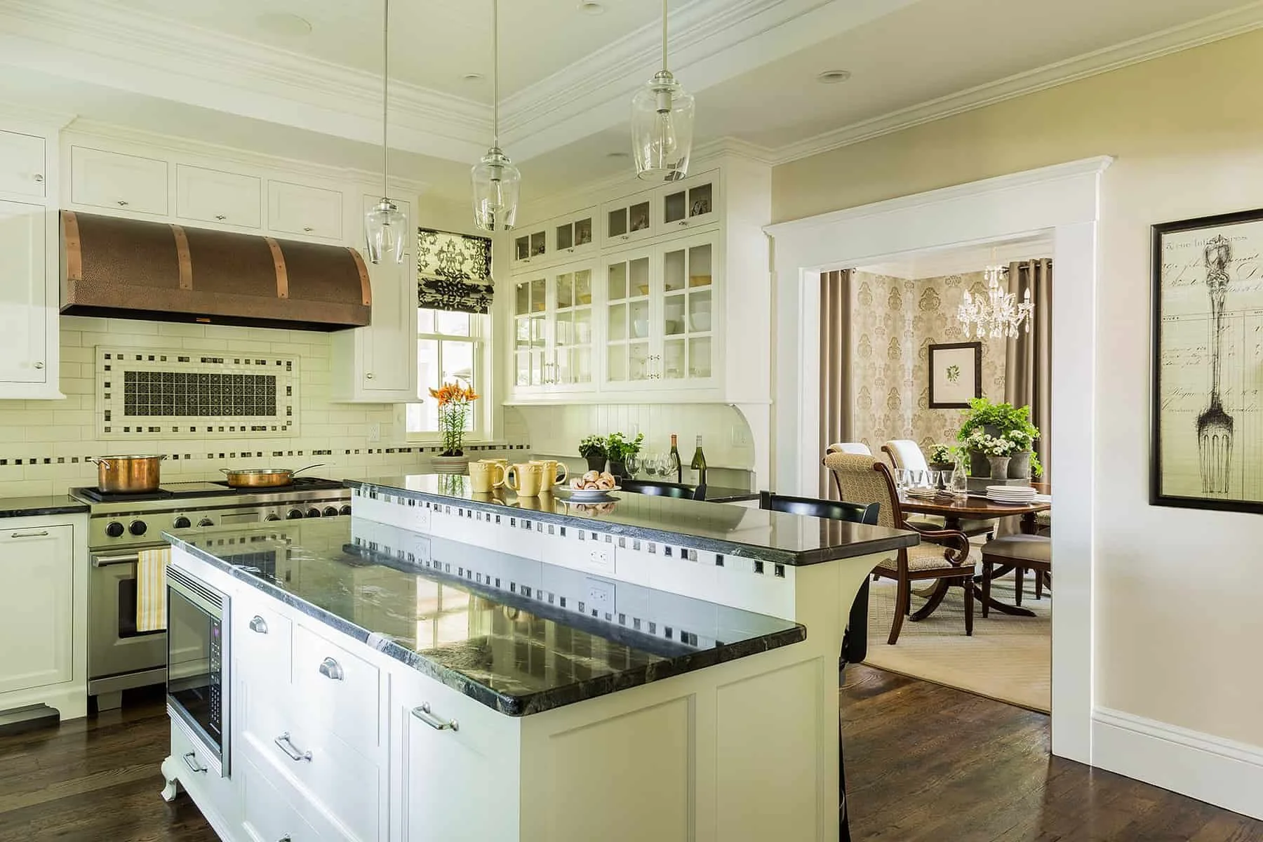 Modern kitchen with granite countertops, white cabinets, stainless steel appliances, and a kitchen island. Adjacent dining room with a round table, chairs, and decor.