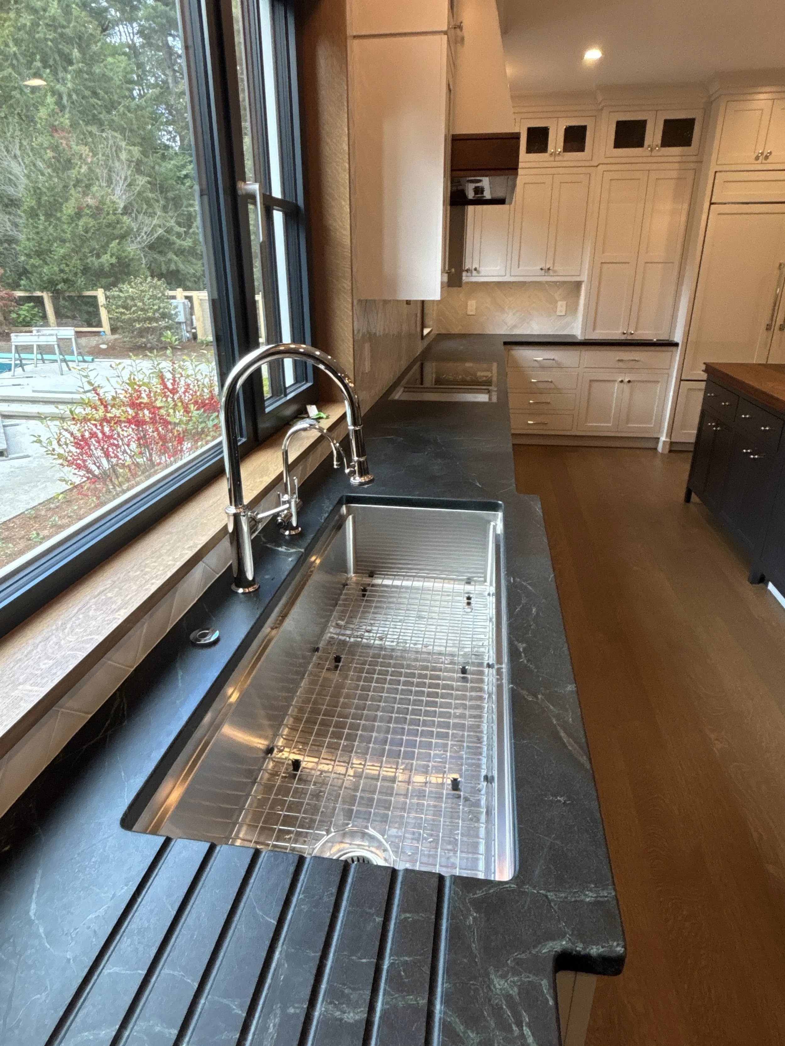Best general contractor, home builder, and home remodeler on the Northshore in Andover, Massachusetts (MA), developed this modern high spacious kitchen with white cabinets, a large central island, pendant lighting, and an energy efficient window.