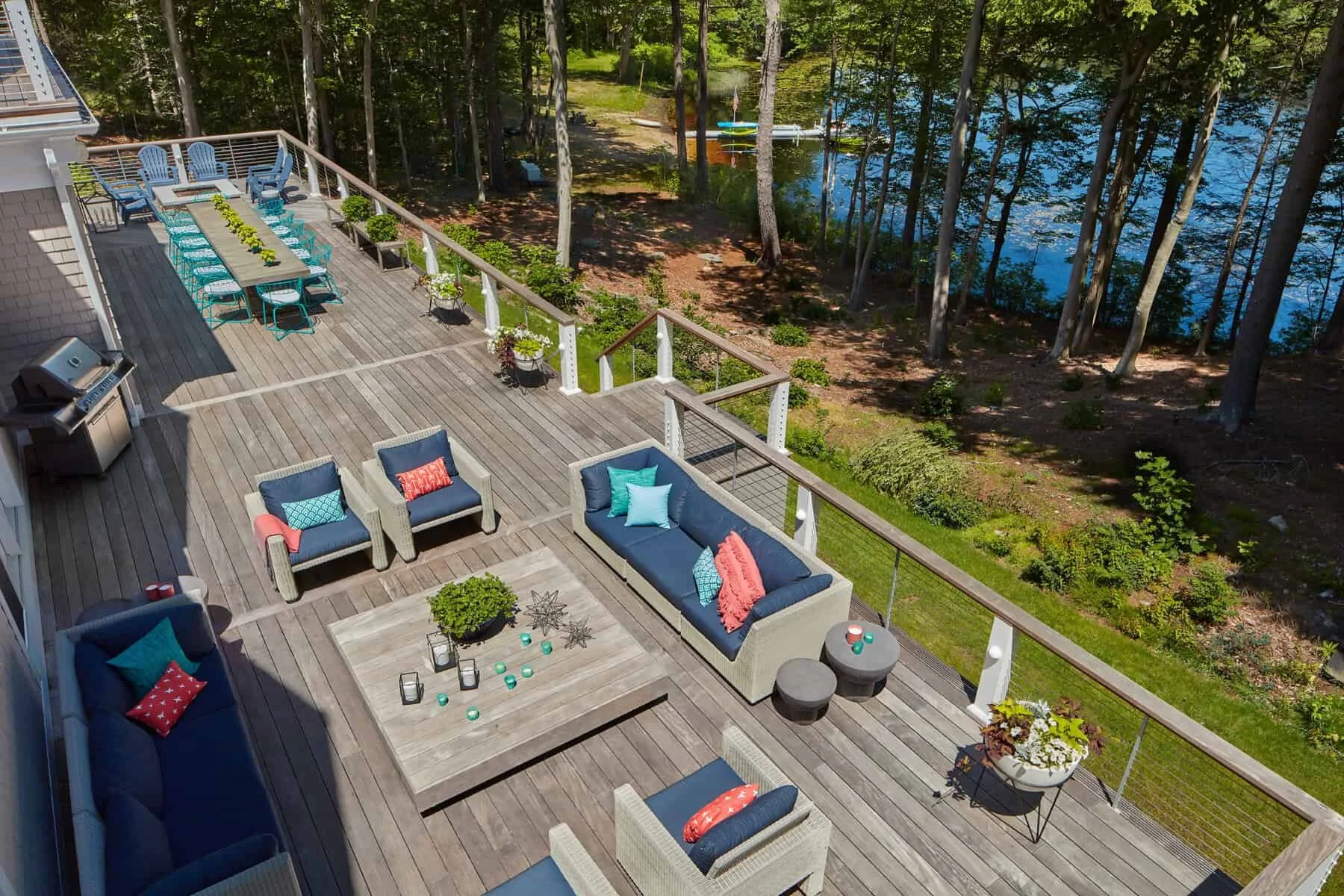 A spacious outdoor deck with seating and a view of a wooded lakeside area.