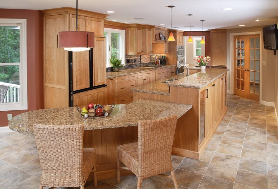 Kitchen with wooden cabinets, granite countertops, tiled floor, a dining table with wicker chairs, and pendant lighting.
