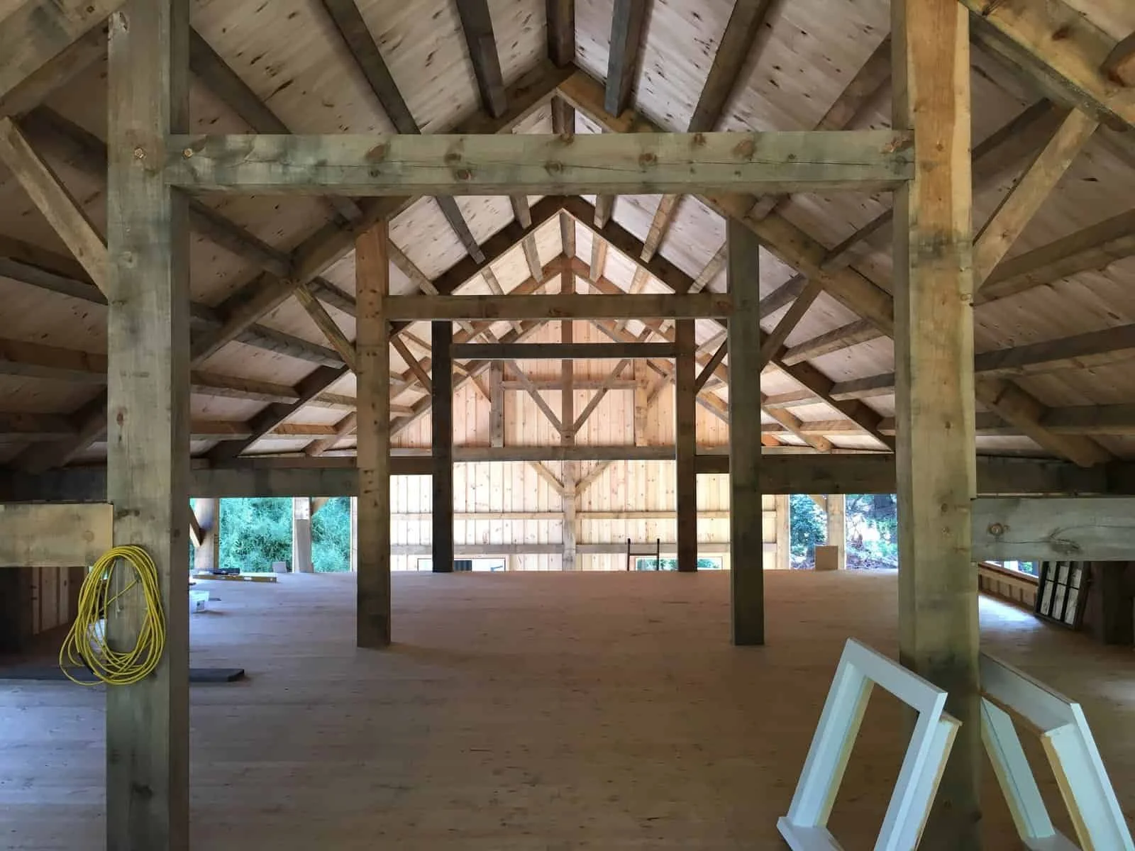 Interior view of a partially constructed wooden building with exposed beams and a spacious open area.