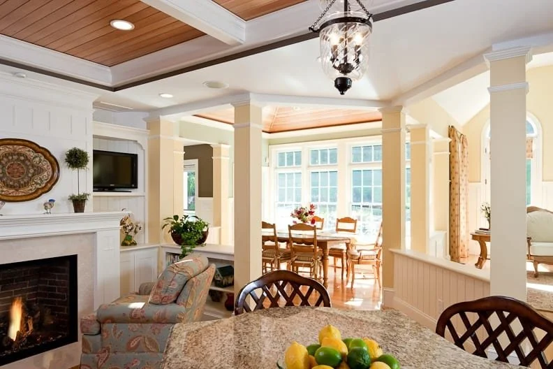Bright open living and dining area with fireplace, large windows, and traditional decor.