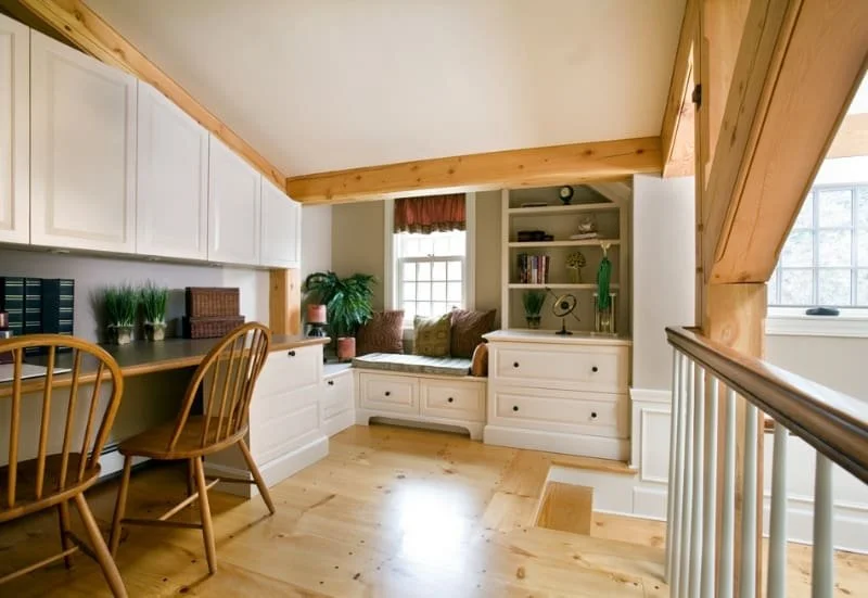 Cozy corner with built-in window seat, bookshelf, and window in a room with wooden accents and natural light.