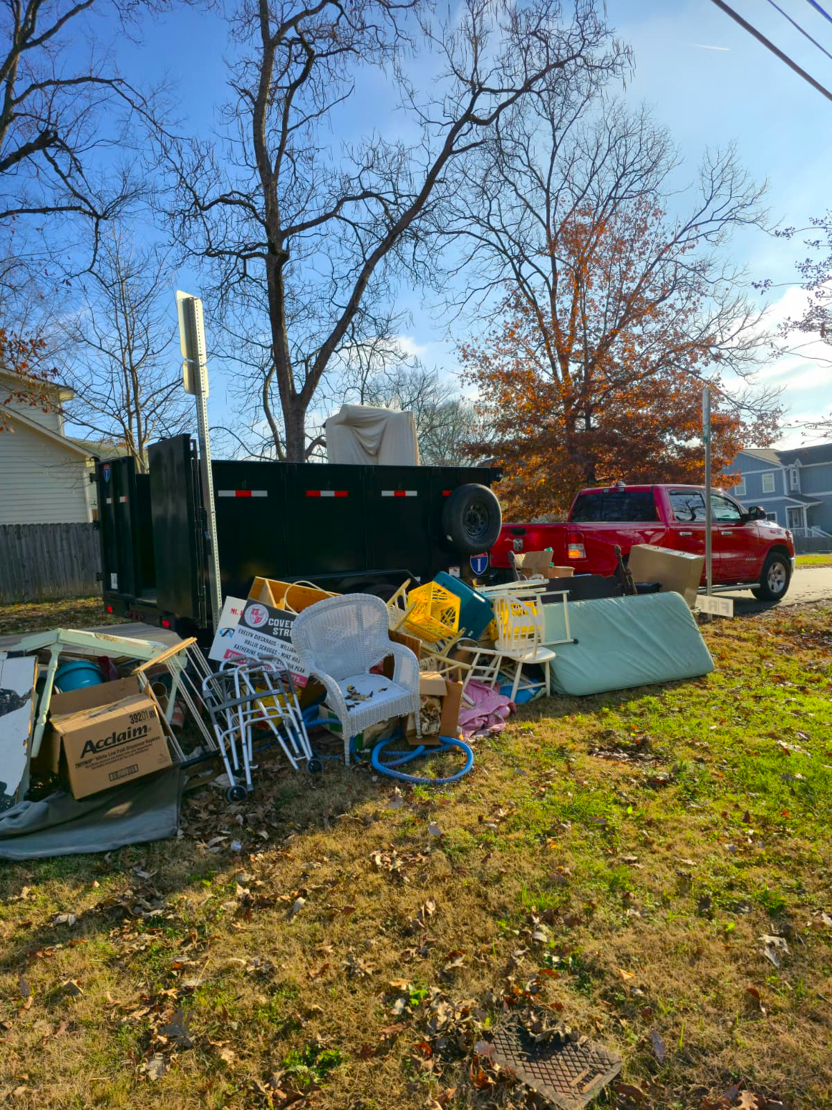 Lorenz Junk Removal trailer parked on the street collecting a large pile of junk in Nashville, Tennessee