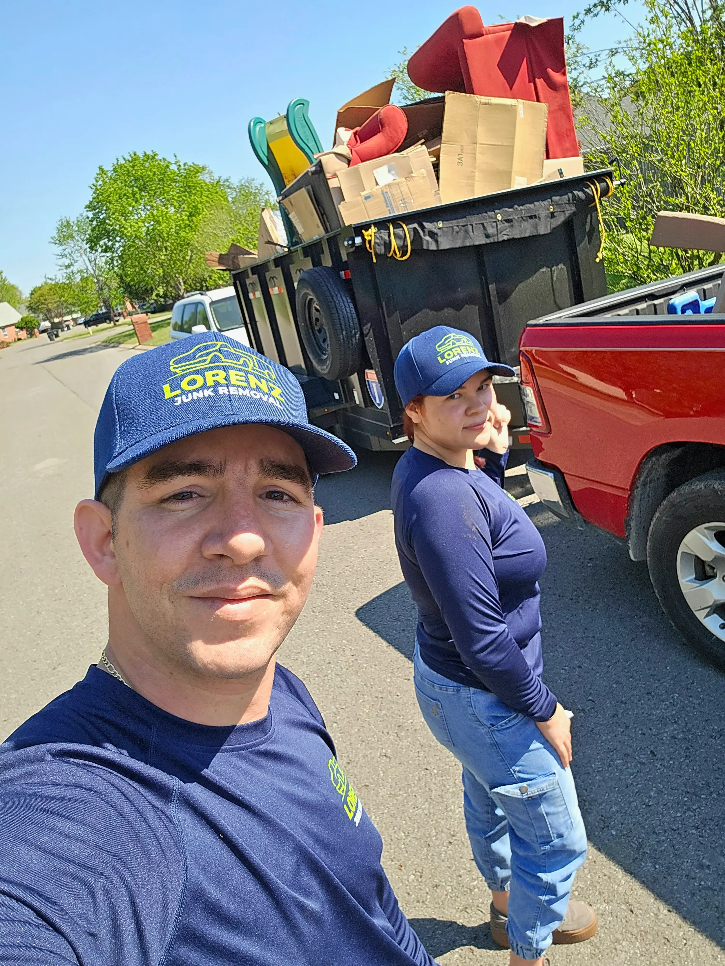 Husband and wife owners standing in front of a dump trailer loaded with junk in Murfreesboro, Tennessee