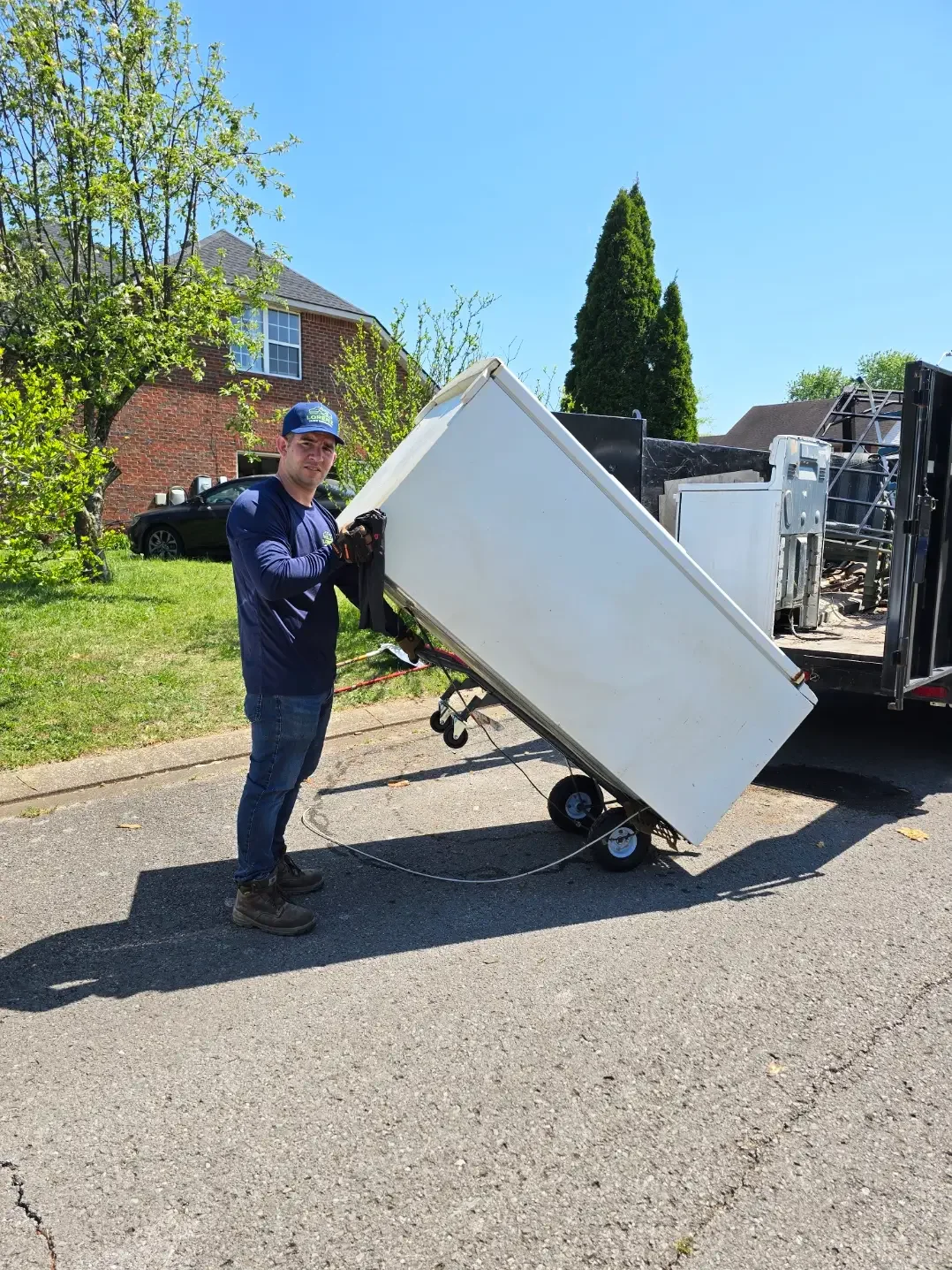 Lorenz Junk Removal hauling off an old refrigerator into a dump trailer in Murfreesboro, TN