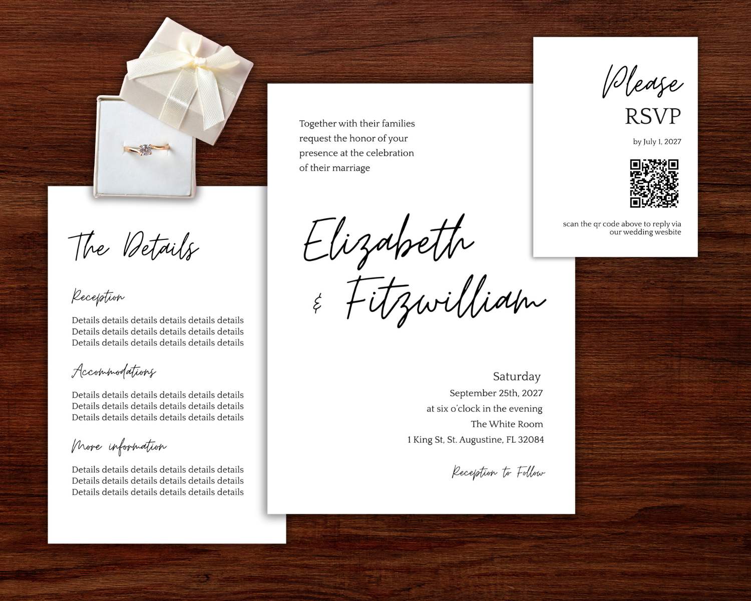 Wedding invitation suite including an RSVP card, a details card, a main invitation card, a small jewelry box with a wedding ring, on a wooden surface.
