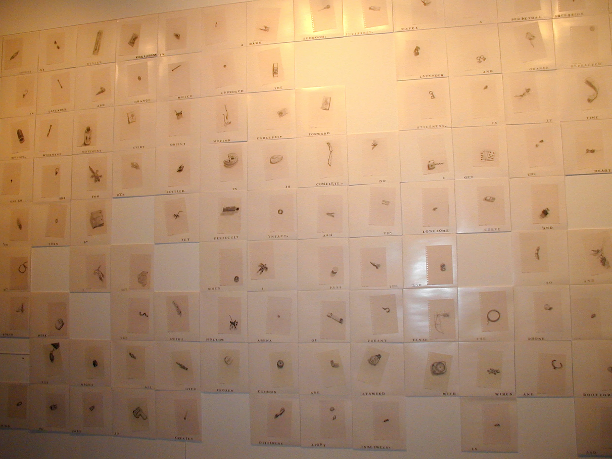 Wall display with numerous white square panels, each containing a word and a small object or illustration, arranged in a grid.