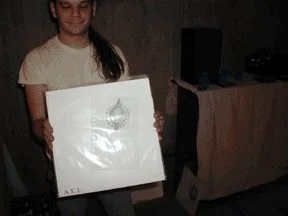 Young girl holding a large white box with a logo or design on it, standing indoors.