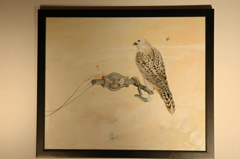 A detailed painting of a bird, possibly a falcon, perched on an old-fashioned mechanical device with a beige background.
