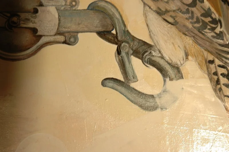 A close-up of a metallic pair of pliers resting on a beige surface with a decorative wheel and a butterfly winged object nearby.