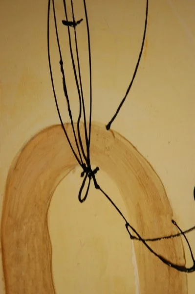Close-up of a wooden surface with black strings tied together and hanging down.