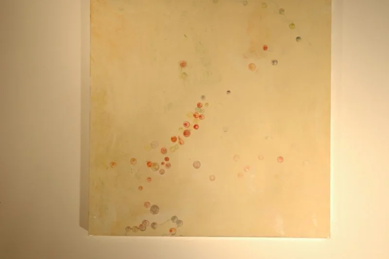 Abstract beige painting with small red, orange, purple, and gray circular dots scattered across the surface.
