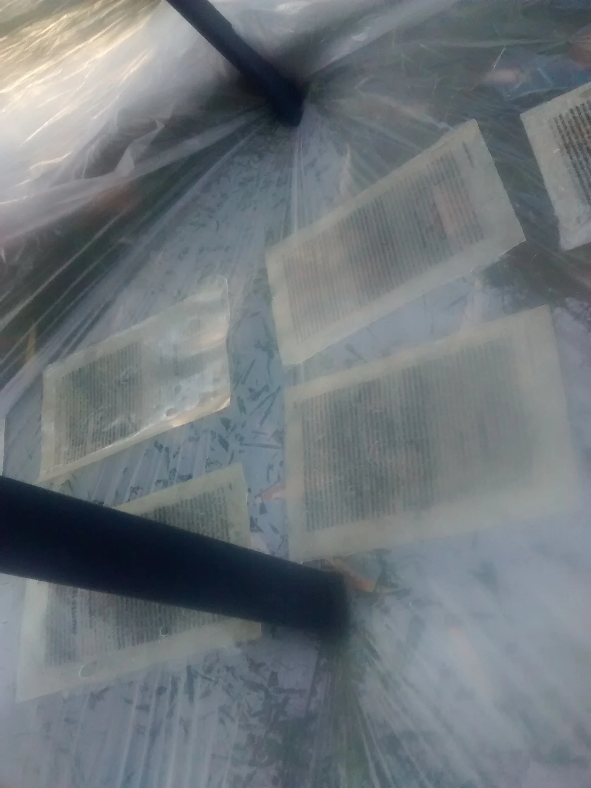 A close-up of papers or documents inside a plastic folder or cover, with a black pen resting on top.
