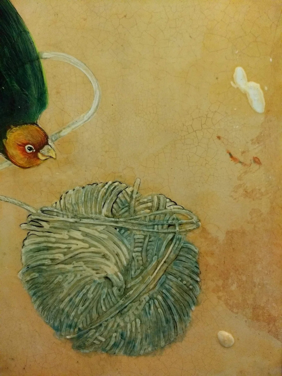 Close-up of a painted decorative surface featuring a bird and a shell on a cracked, beige background.