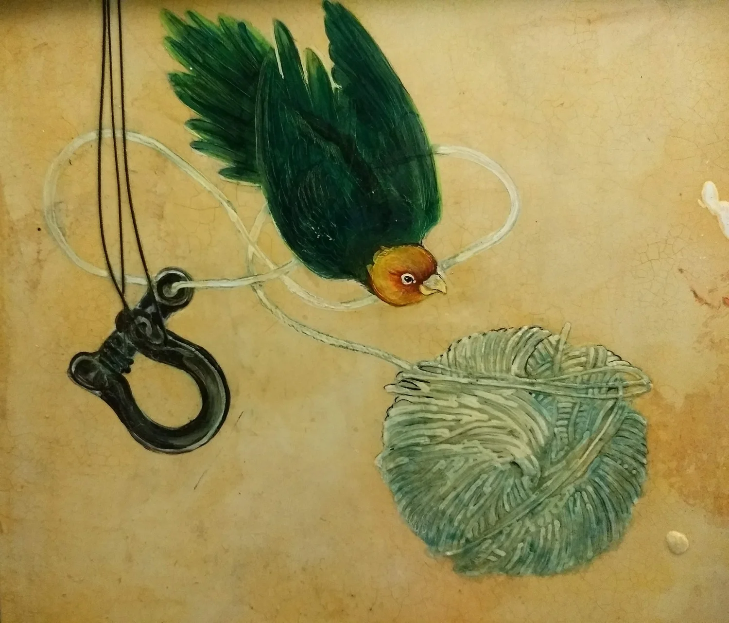 Painted illustration of a bird with green wings and a brown head, hanging upside down from a white string, pecking at a large green ball of yarn, with a black clip attached to the string.