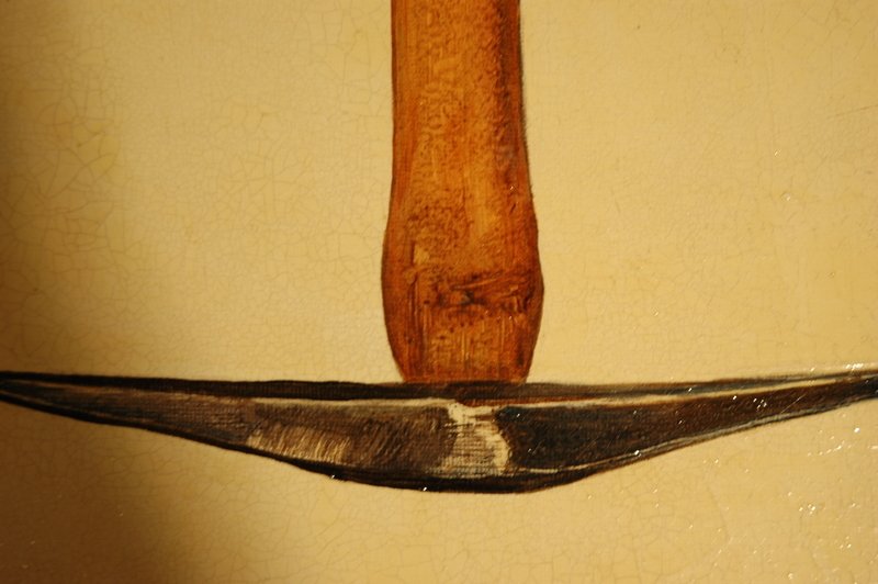 Close-up of a wooden handle and a metal spoon or spatula on a textured beige surface.