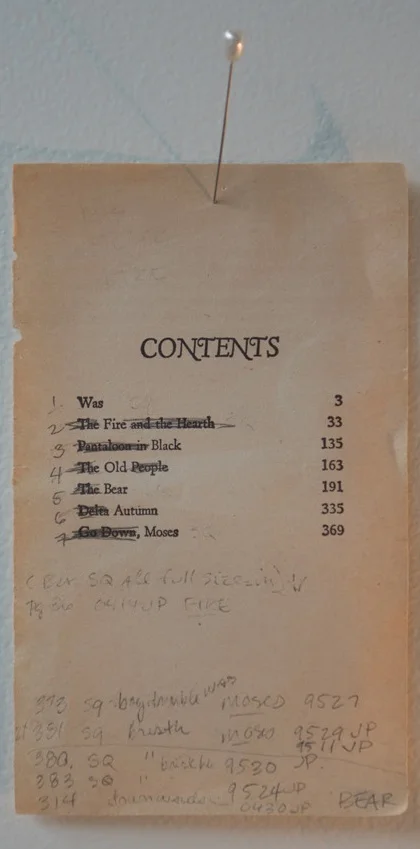 A antique-looking paper bookmark with the word 'CONTENTS' at the top and seven listed chapters with their page numbers, and a lit matchstick inserted at the top. The bookmark appears worn and aged.