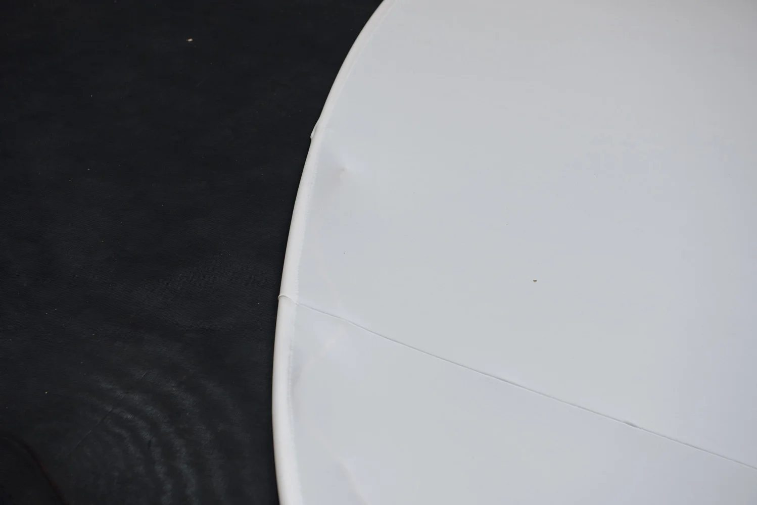 Close-up of the edge of a white object, possibly a plate, with a smooth surface, against a dark textured background.