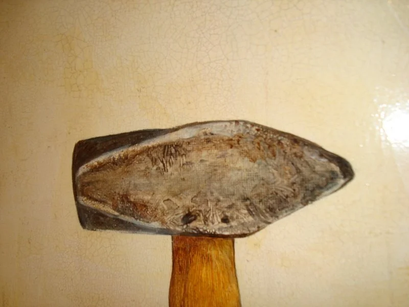 A close-up of a stone tool mounted on a wooden handle, with a textured, crackled beige background.