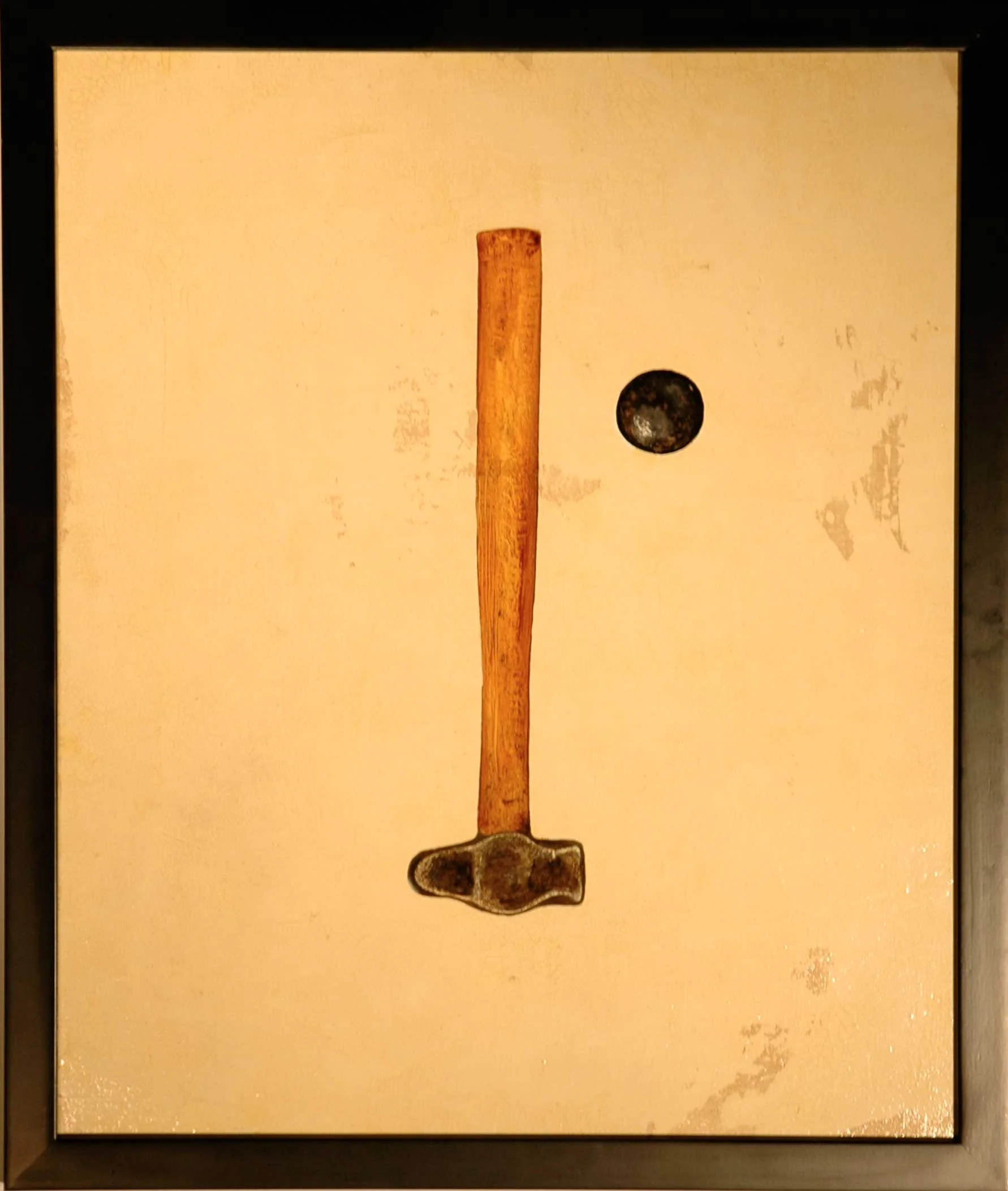 Photo of a wooden hammer, a black ball, and a beige background, arranged to resemble a face.