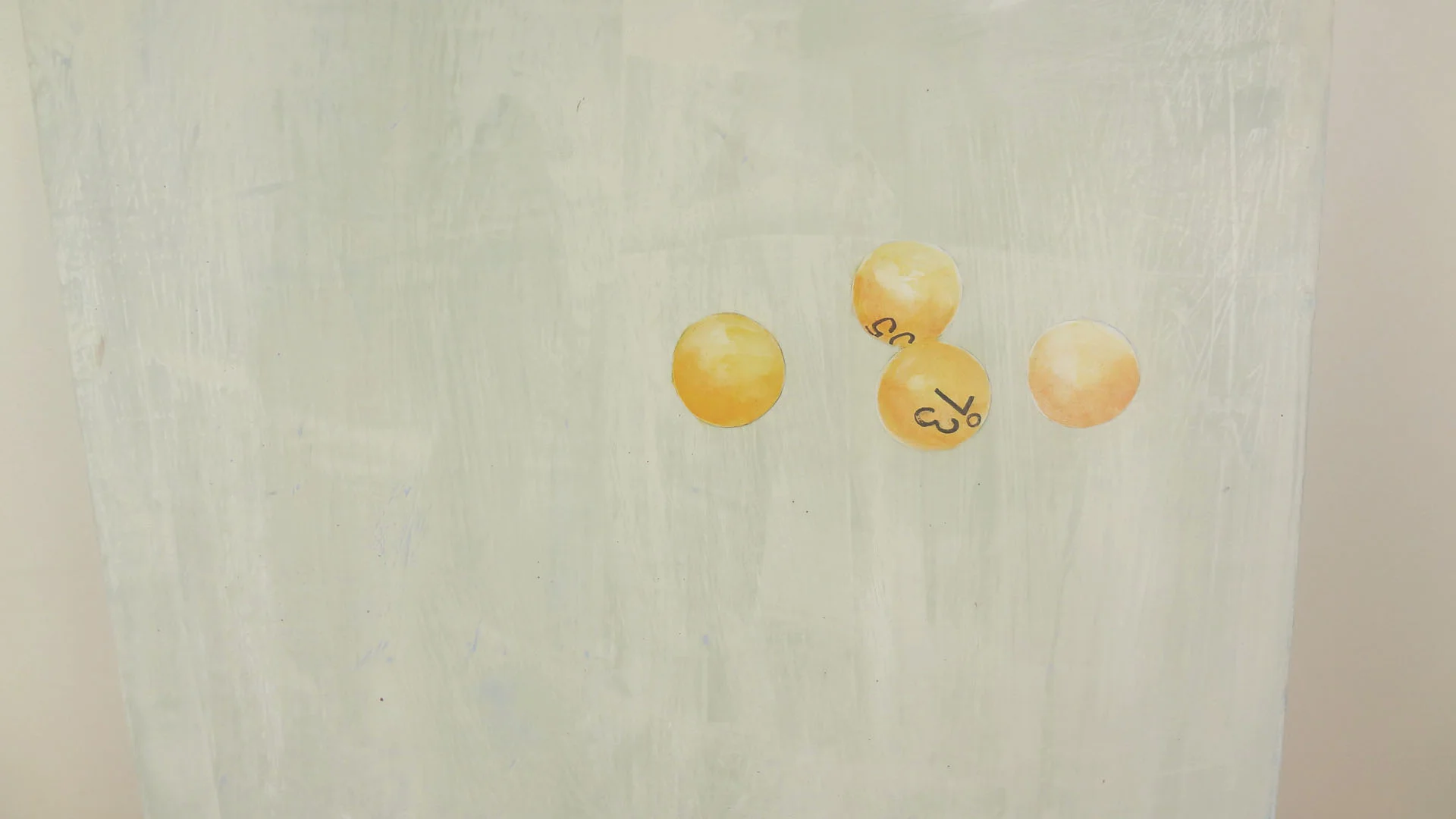 Four yellow lottery balls with black numbers on a light surface.