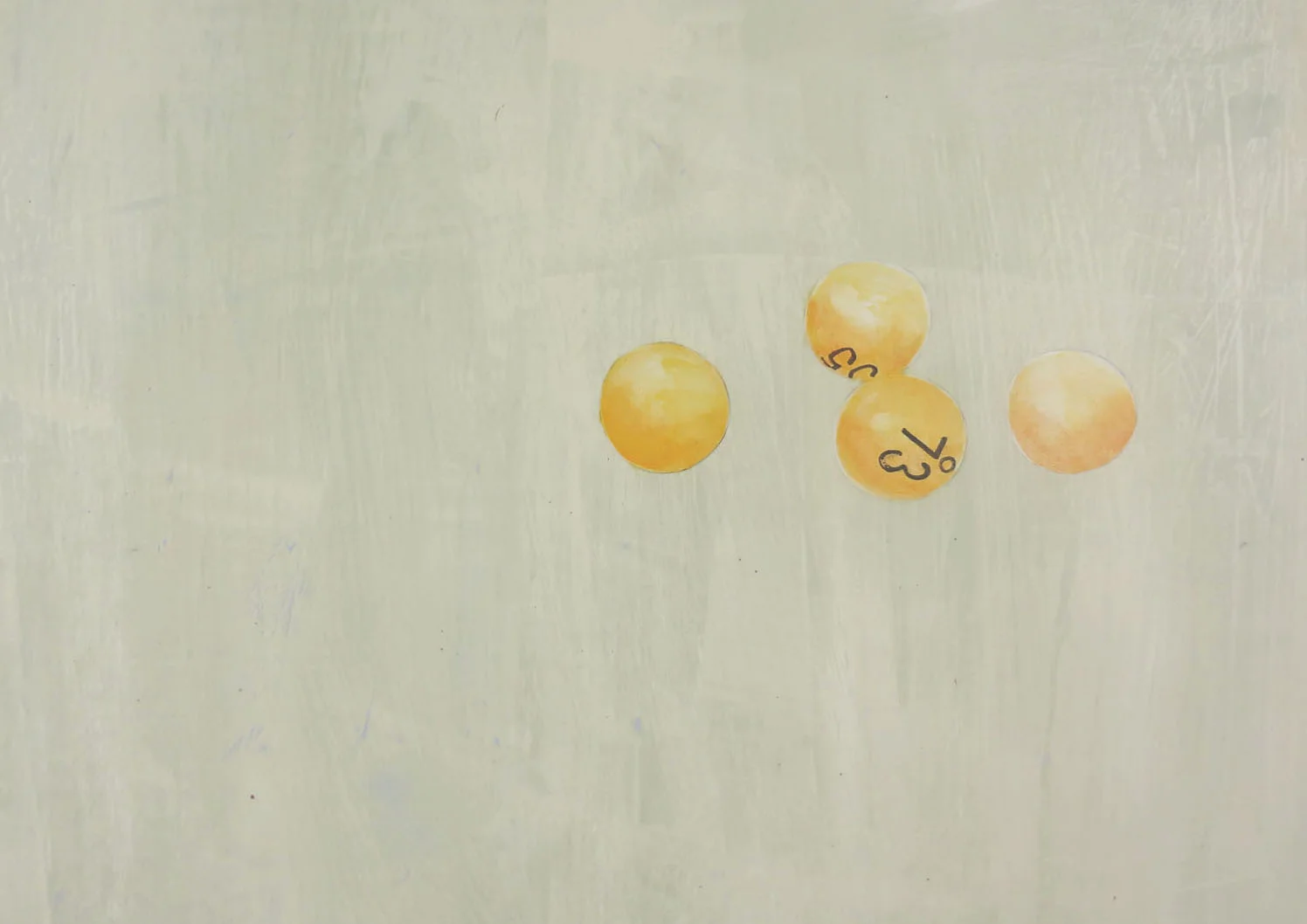 Four yellow lottery balls with printed numbers, two of which show part of the numbers 73 and 14, on a light-colored surface.