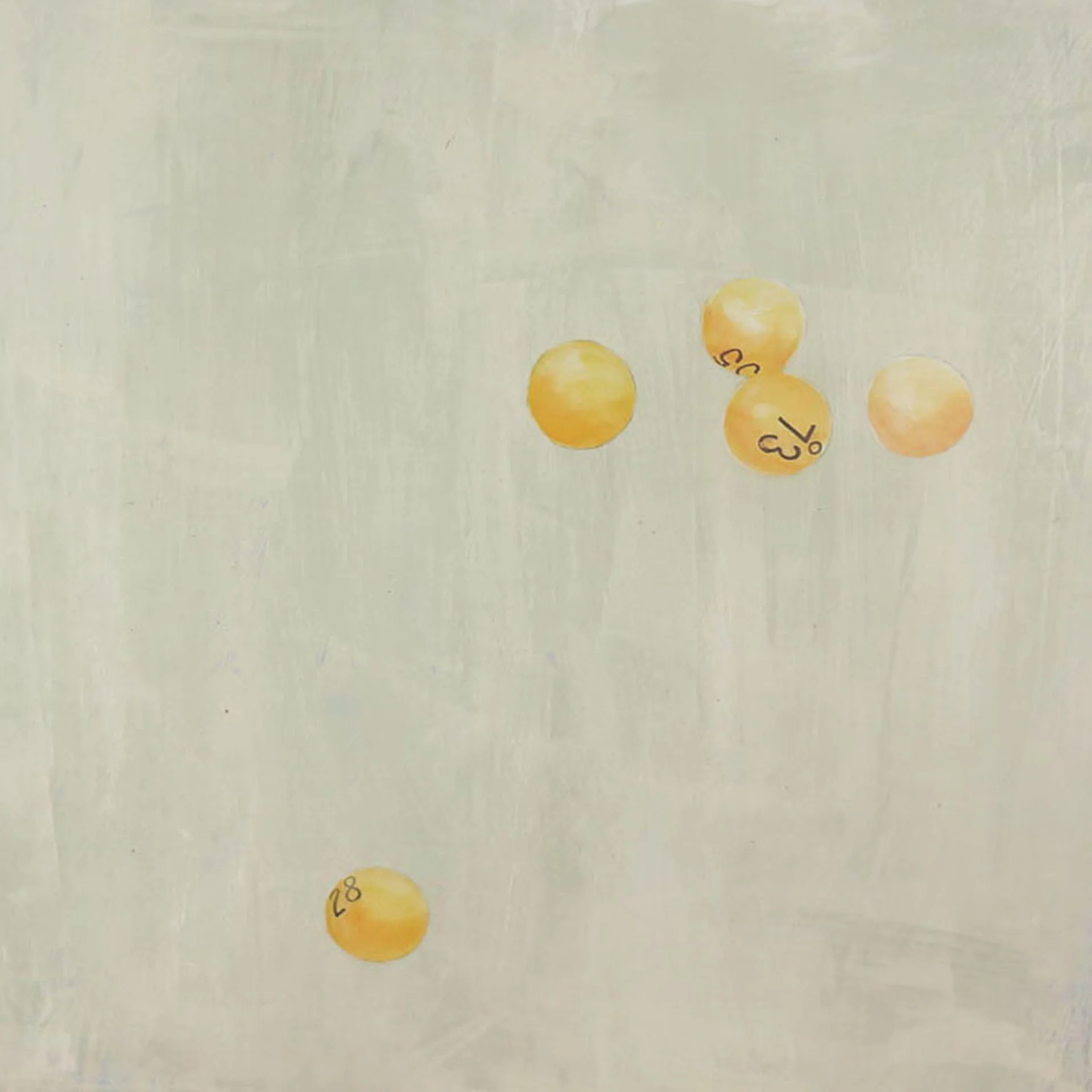 A close-up photograph of yellow lottery balls with black numbers on a light surface.