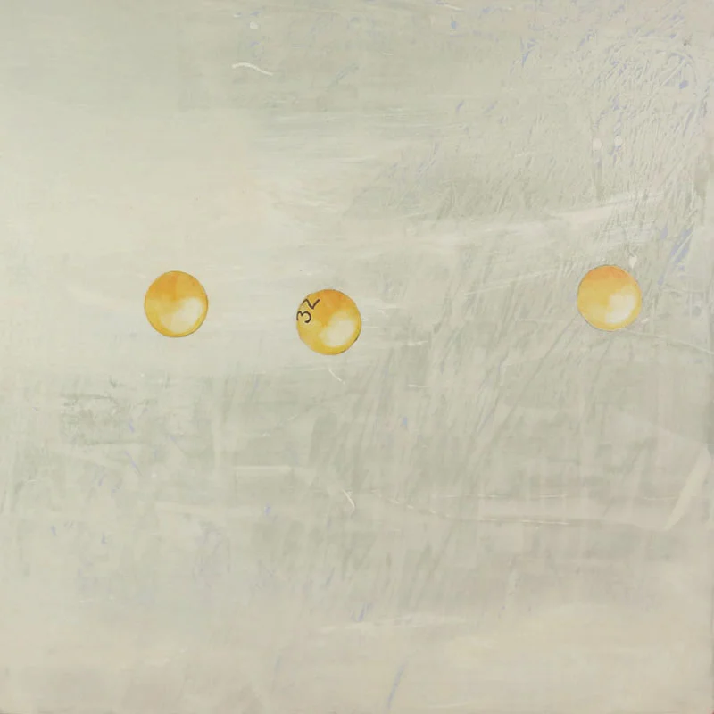 Three yellow golf balls on a light-colored surface, with the middle ball having the number 32 written on it.