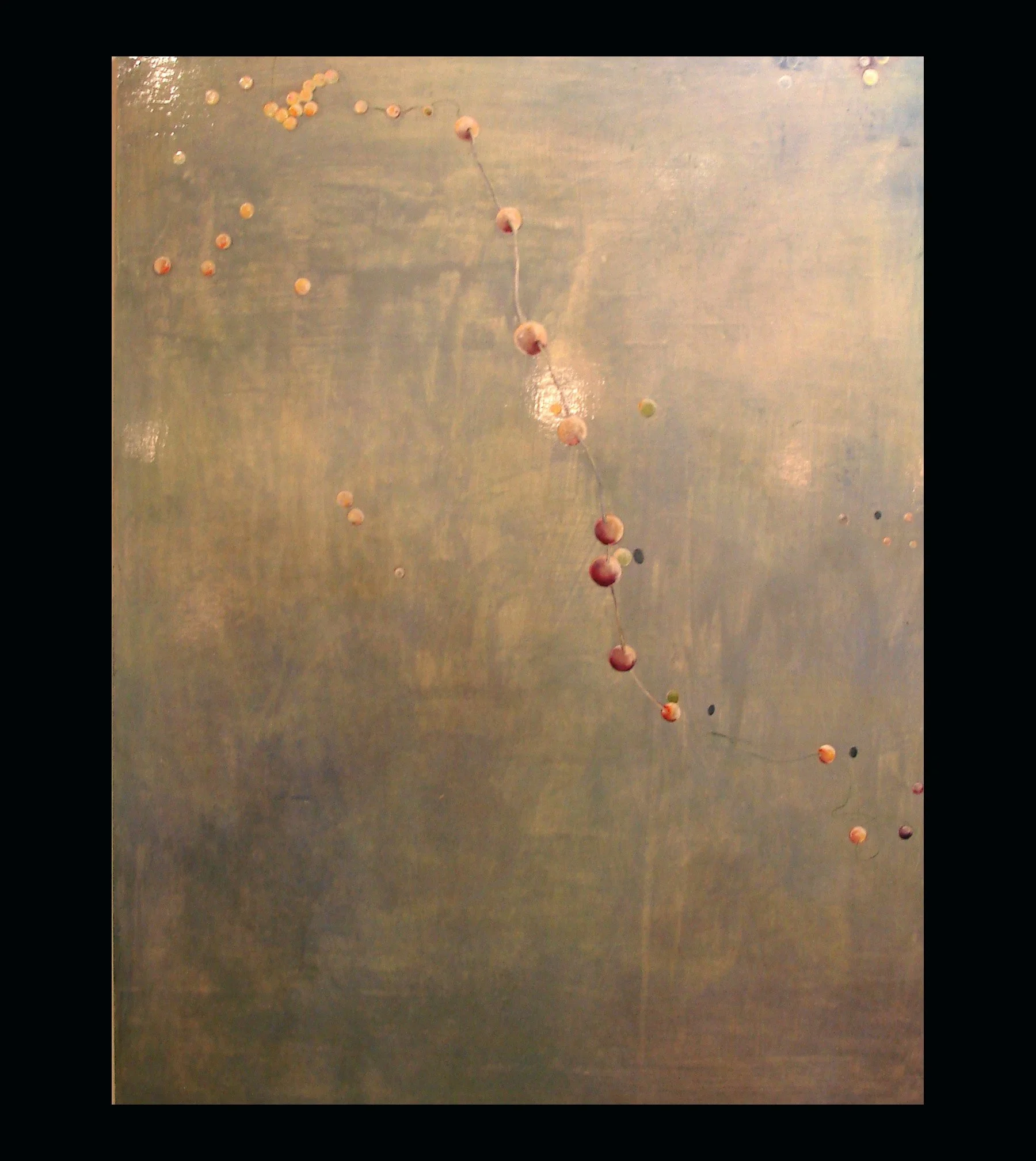 Close-up of a metallic surface with a string of small beads and bubbles attached, reflecting light.