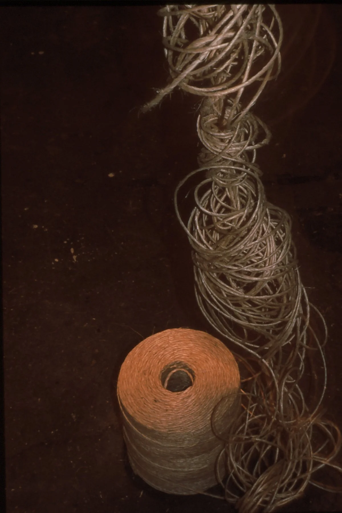 Spools of brown thread and a tangled ball of thin, brown wire on a dark surface.