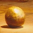 A gold-colored sphere resting on a wooden surface.