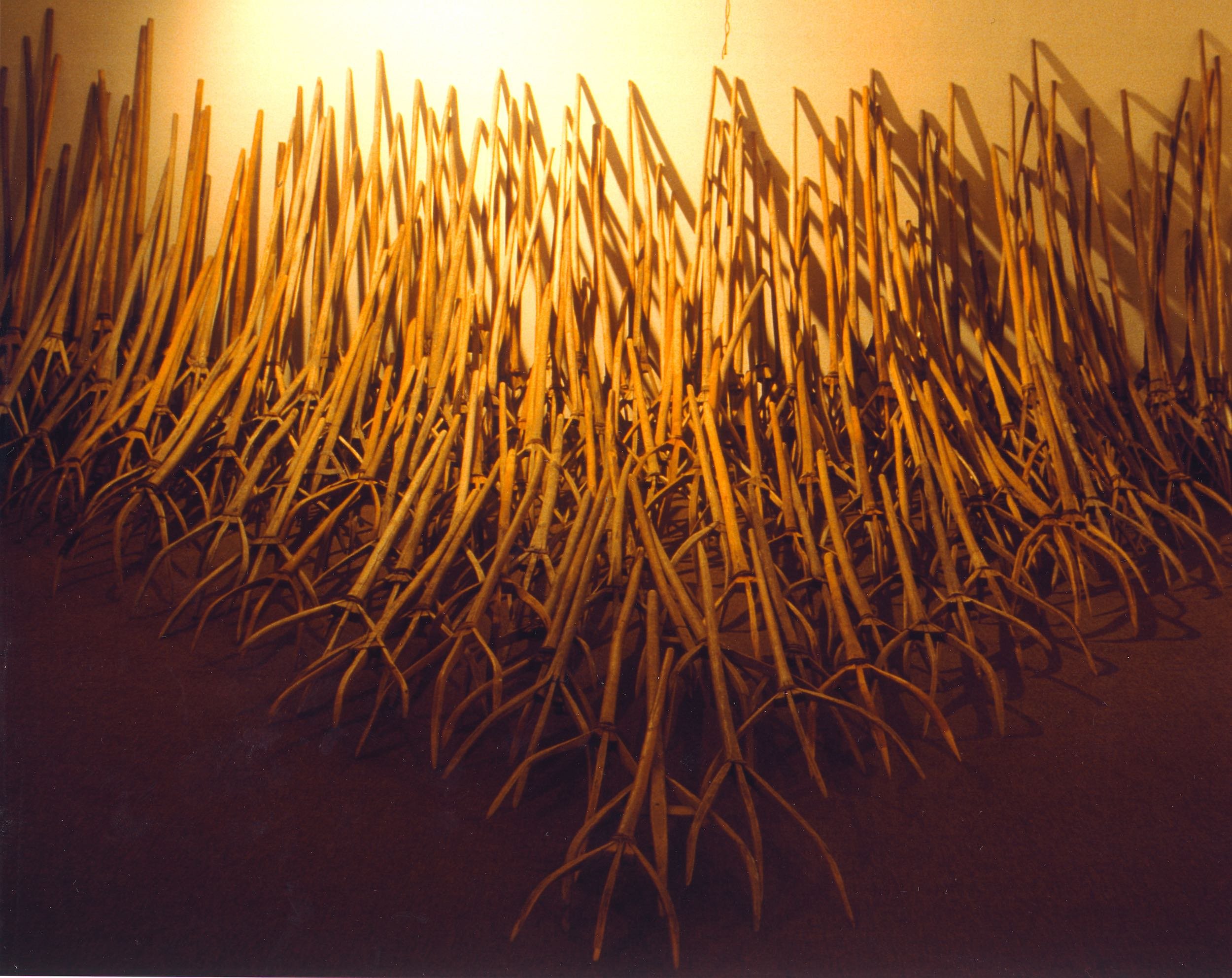 An art installation featuring a field of large, intertwined, orange-colored wheat stalk sculptures.
