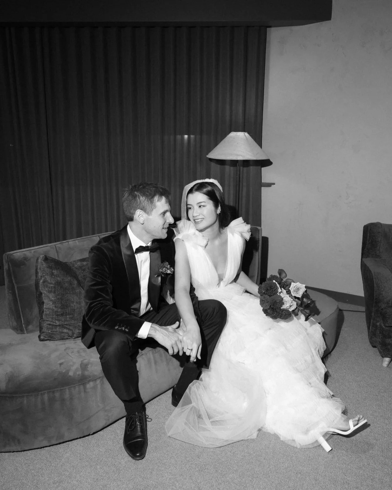 The couple share a quiet, cinematic pause on a velvet couch at Monster Kitchen & Bar. A flash-lit frame — elegant, modern, and tinged with intimacy.