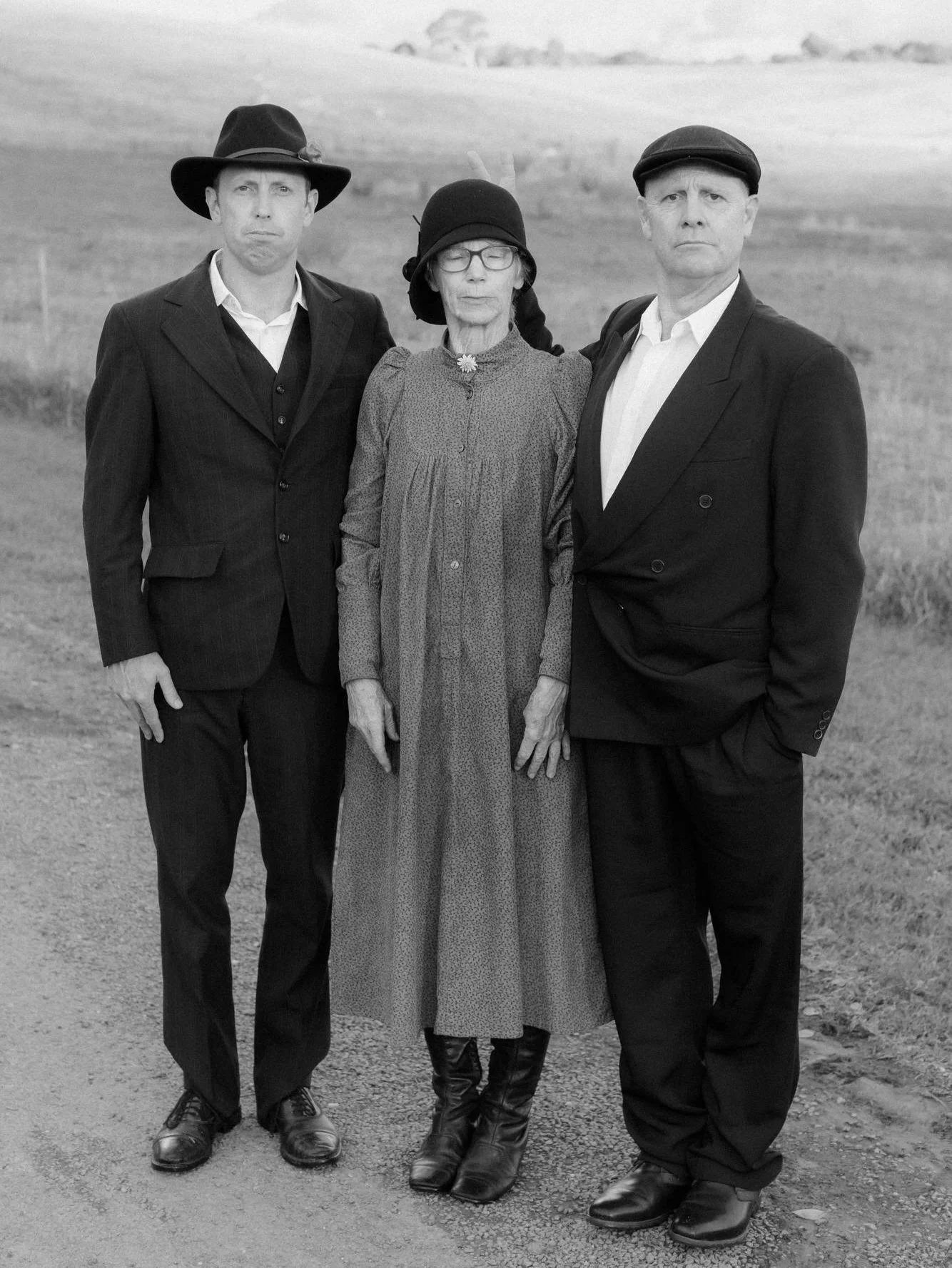 A family portrait with a touch of mischief — formal wedding photography meets playful rebellion, captured against the rolling hills near Canberra