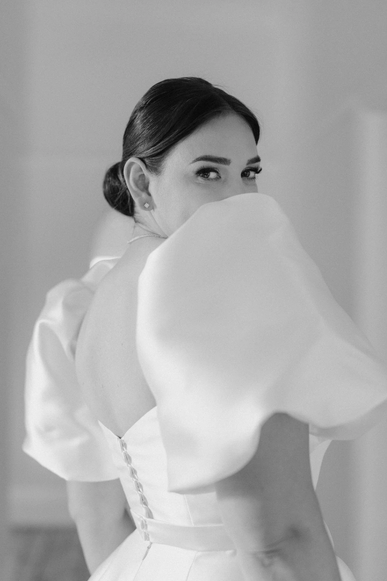 Elegant bridal portrait at Kimo Estate in Gundagai, with the bride looking over her shoulder in a sculptural puff-sleeve gown, captured in timeless black and white by Corinna & Dylan