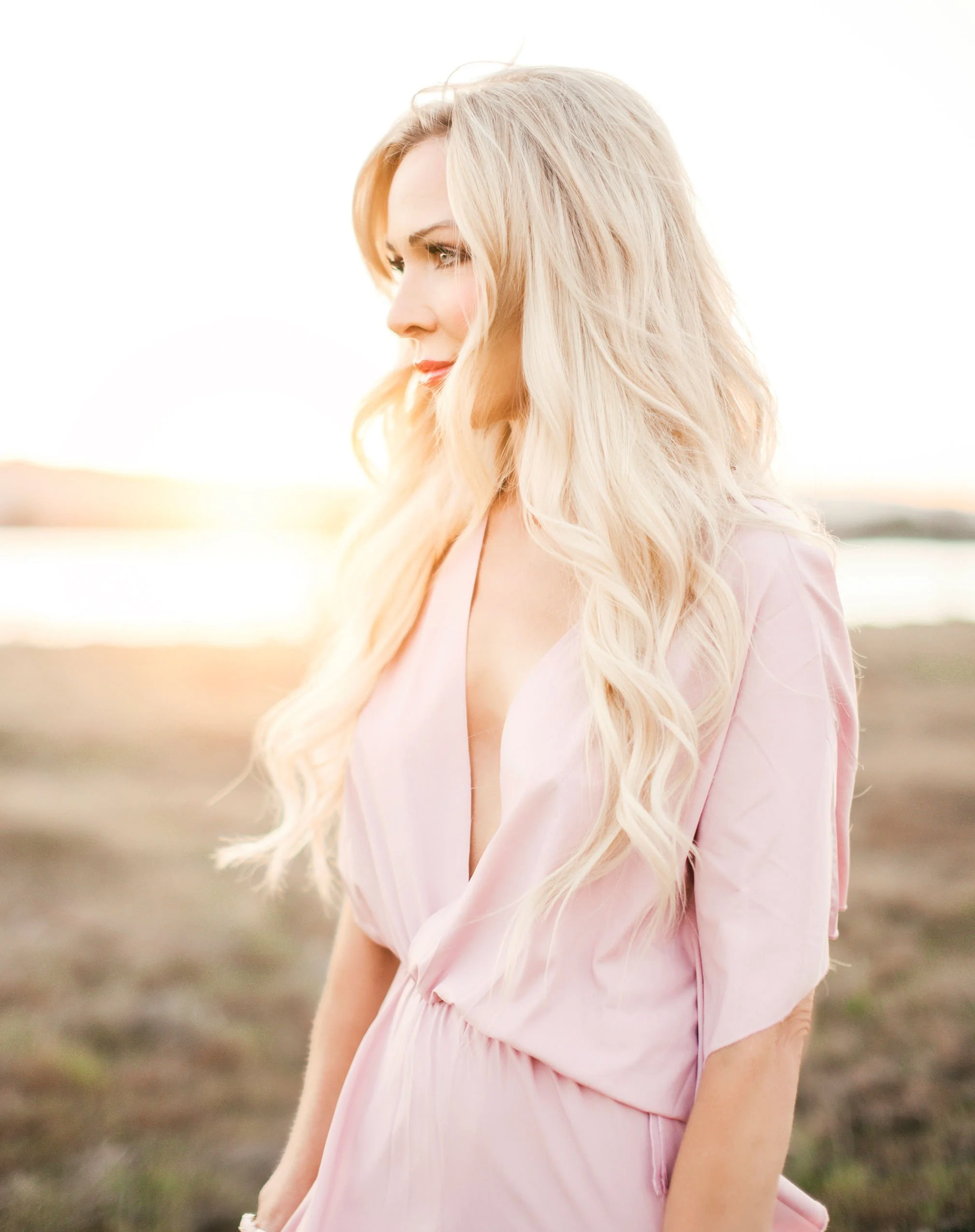 JoDee Anderson of Oregon looking at a distance, standing in a field, with a pink dress on, standing in the sunlight