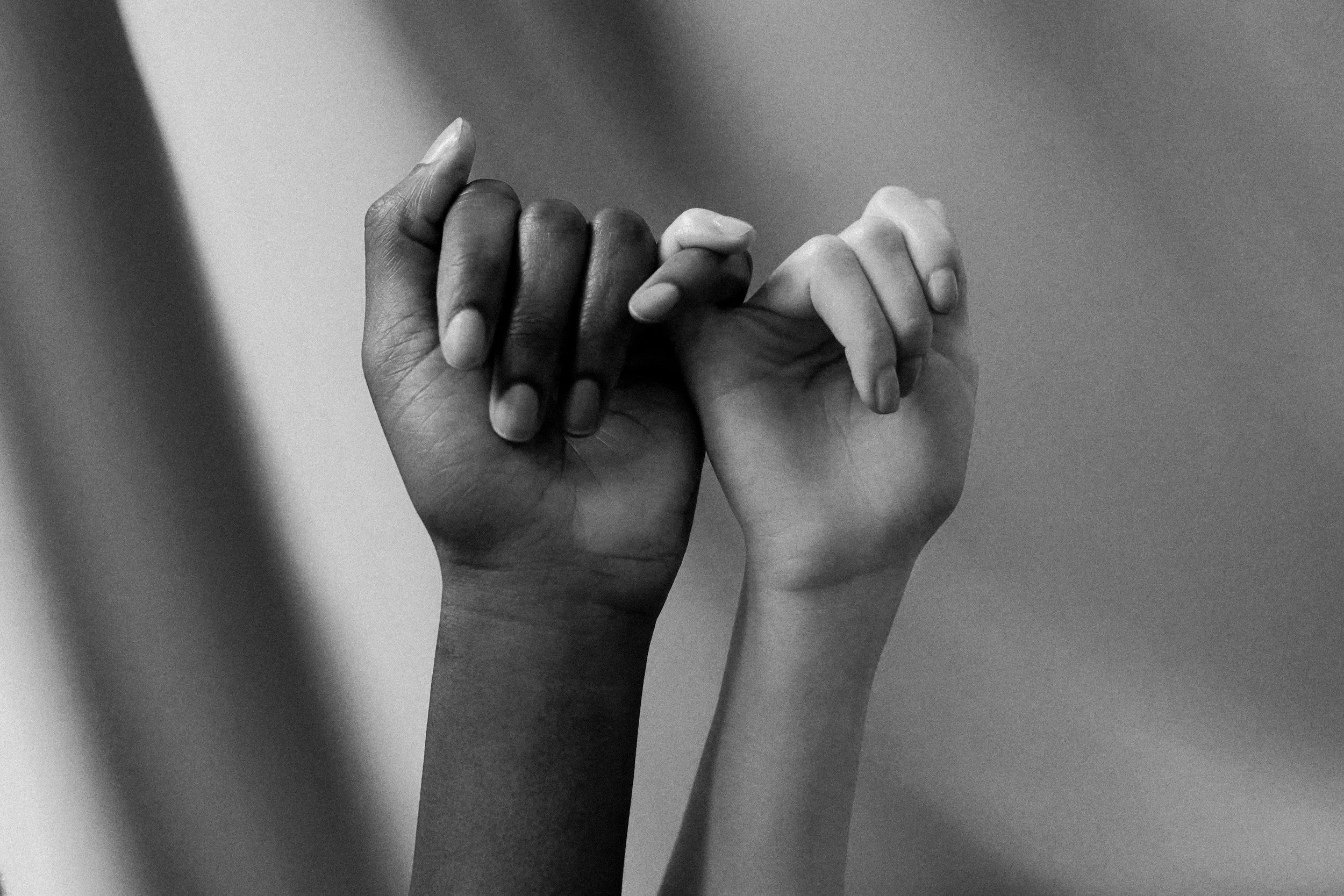 Perimenopause. Two hands, one dark-skinned and one light-skinned, clasped together in a fist bump.