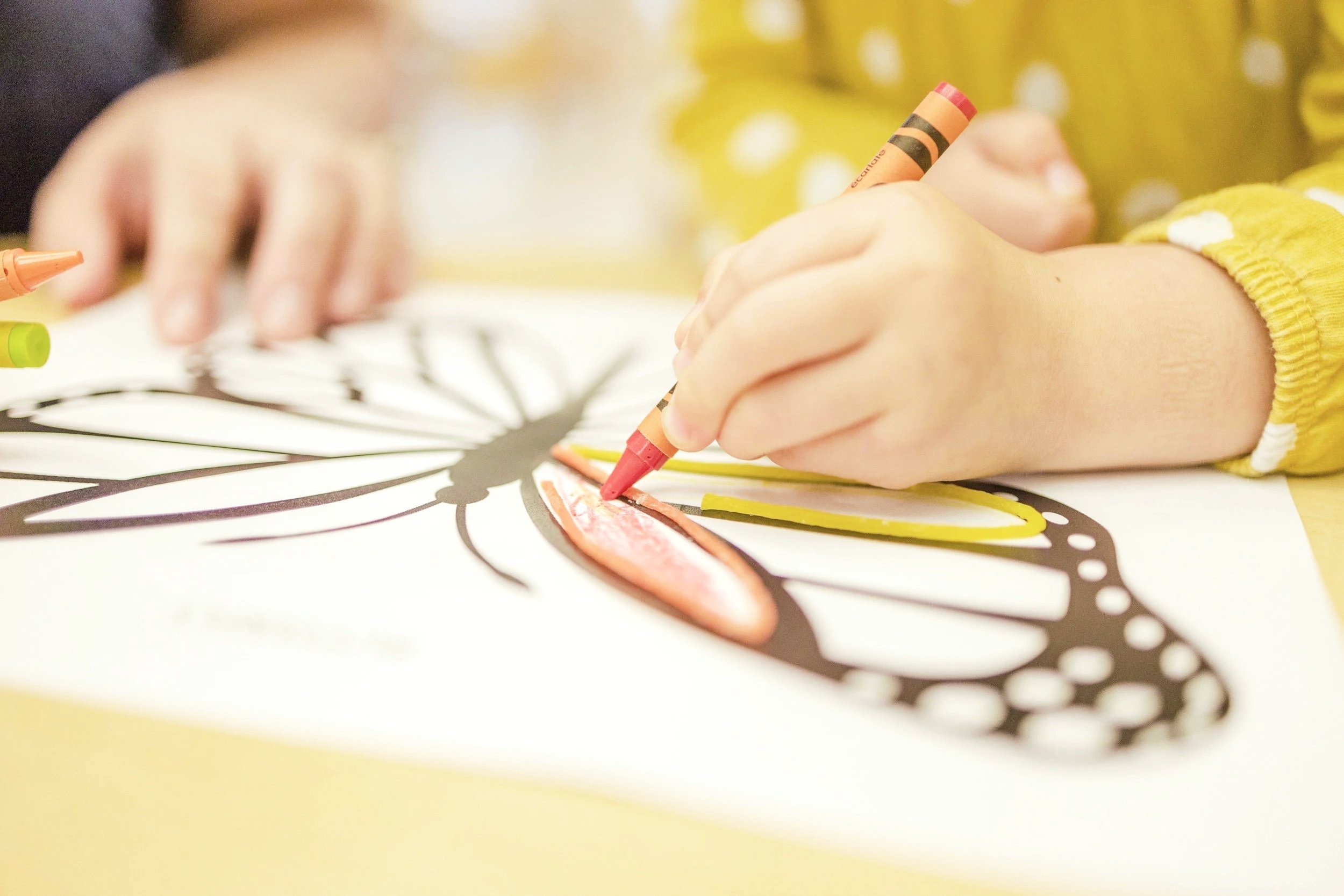 Child coloring a zebra illustration using crayons on paper. Parenting therapy online in California.