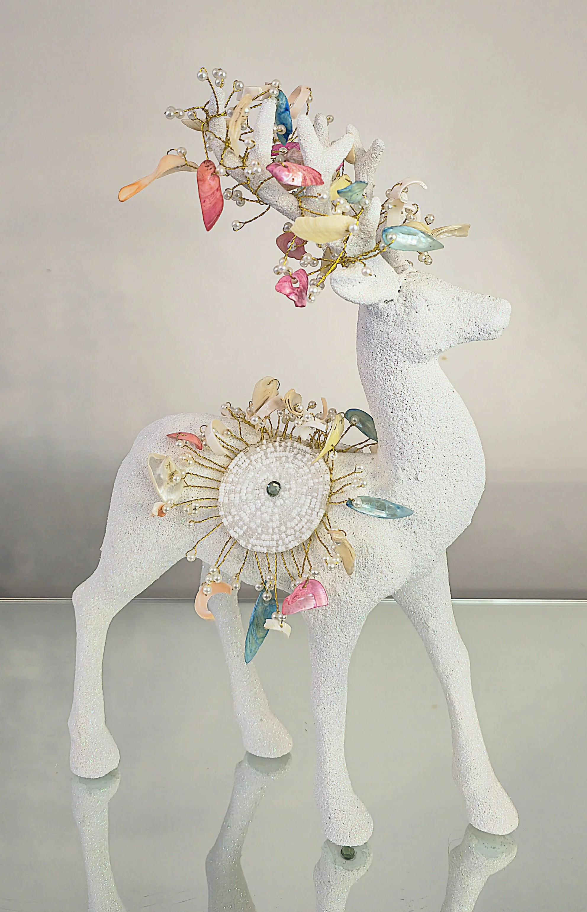 statue de cerf en blanc avec des décorations colorées sur ses bois, symbôle de Noël ou décoration festive.