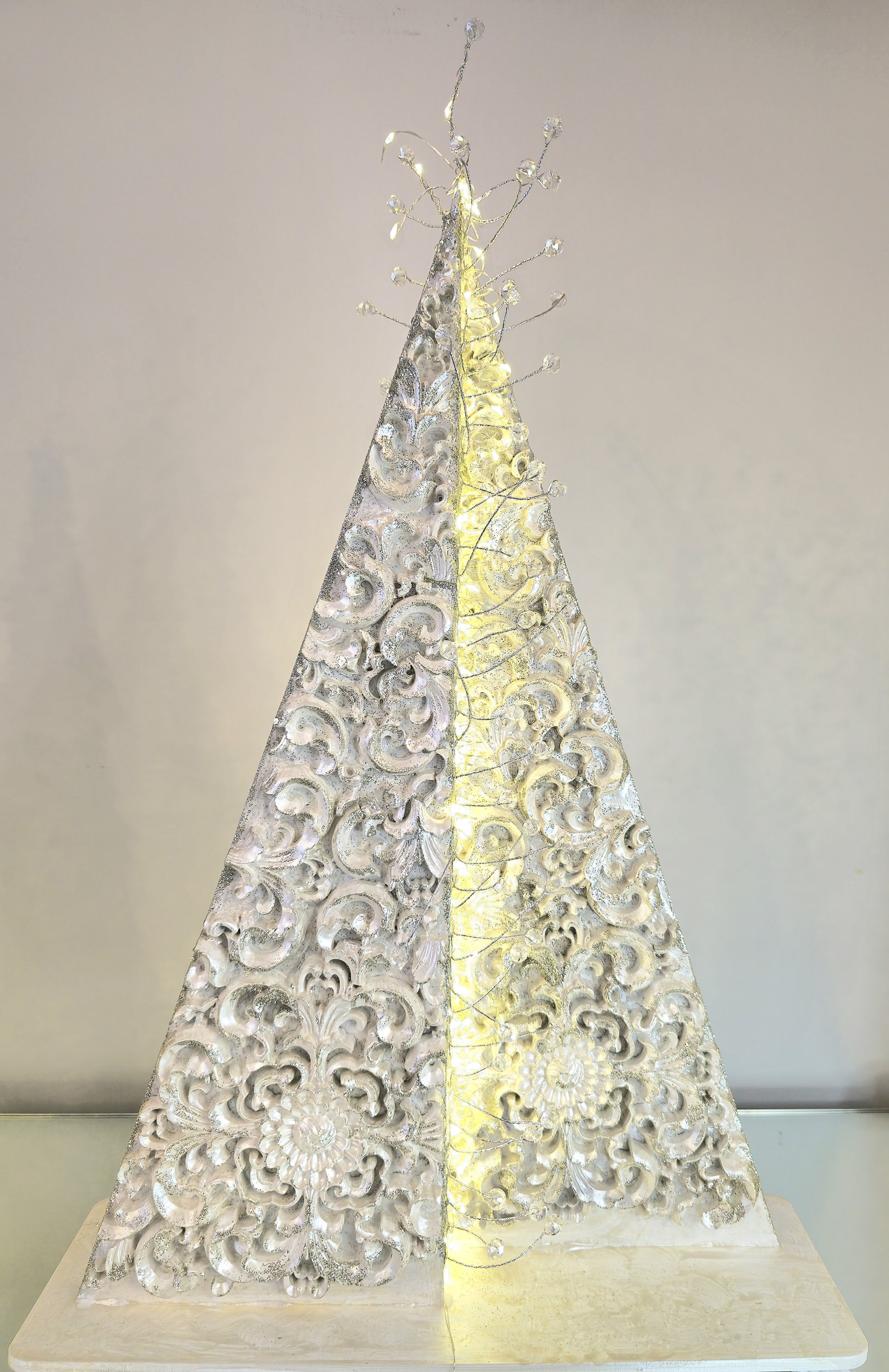 Décoration de Noël avec deux pyramides en ornement blanc, éclairées et ornées de fil LED.